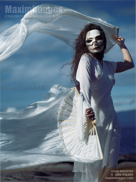 Stock photo of Mysterious asian woman in white face mask and dress dancing gracefully with white silk hand fans Buy commercial use license at MaximImages