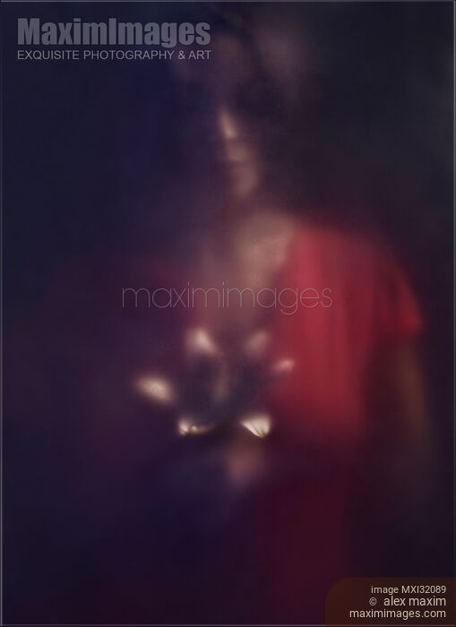 Mysterious dark portrait of a woman looking at a lily flower in her hands behind hazy glass in darkness Stock photo of Mysterious dark portrait of a woman looking at a lily flower in her hands behind hazy glass in darkness Buy commercial use license at MaximImages