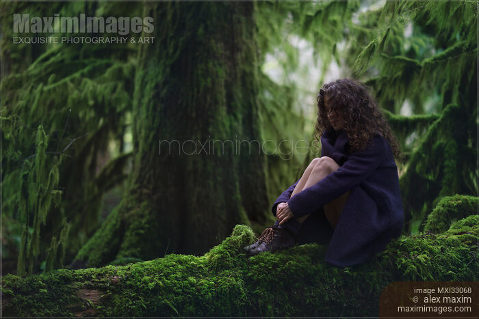 Nostalgic tranquil moody nature scenery of a woman sitting on mossy tree trunk in green forest scenery Stock photo of Nostalgic tranquil moody nature scenery of a woman sitting on mossy tree trunk in green forest scenery Buy commercial use license at MaximImages