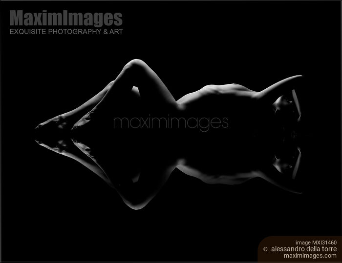 Nude woman lying on black background with a mirrored reflection Stock photo of Nude woman lying on black background with a mirrored reflection Buy commercial use license at MaximImages