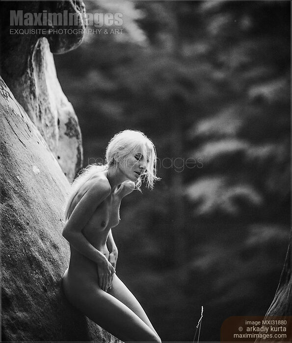 Stock photo of Nude woman with long white hair leaning against the rocks in the nature Buy commercial use license at MaximImages