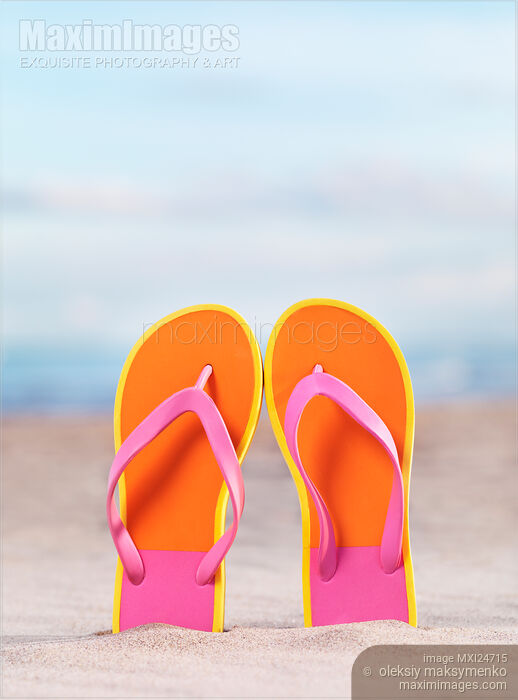 Stock photo of Pair of bright orange flip flops at the beach Buy commercial use license at MaximImages