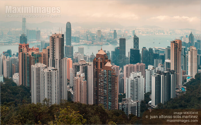 Stock photo of Panoramic sunset scenery of Hong Kong city in China with high-rise modern buildings in the mist Buy commercial use license at MaximImages