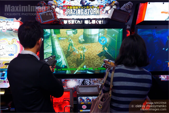 Stock photo of People playing Razing Storm arcade slot machines Buy commercial use license at MaximImages