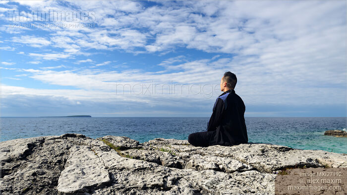 Person meditating on a shore of a lake Stock photo of Person meditating on a shore of a lake Buy commercial use license at MaximImages