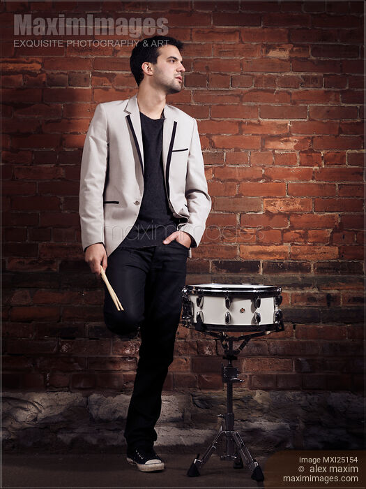 Stock photo of Portrait of a drummer standing at a wall Buy commercial use license at MaximImages