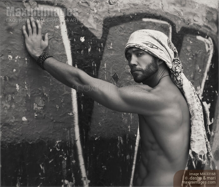 Portrait of a sexy handsome bearded man with bare torso wearing bandana leaning against graffiti wall Black and white Stock photo of Portrait of a sexy handsome bearded man with bare torso wearing bandana leaning against graffiti wall Black and white Buy commercial use license at MaximImages