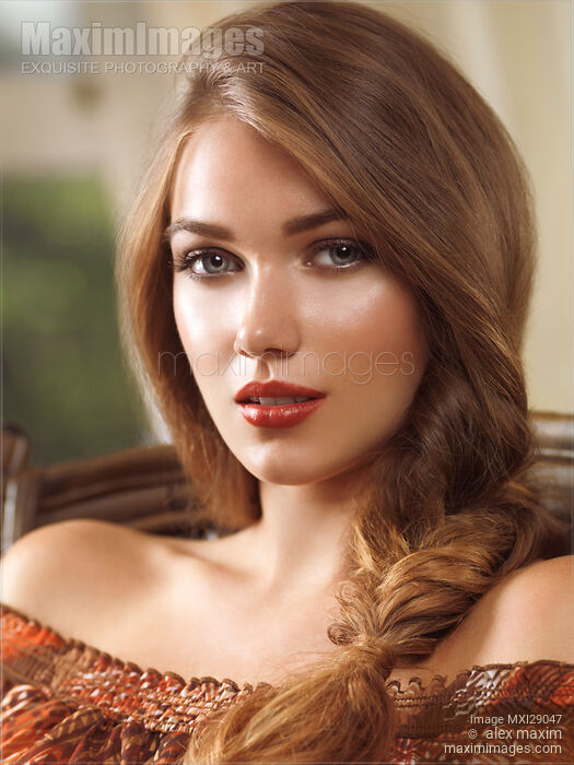 Stock photo of Portrait of a young woman with hair in a braid sitting in a chear Buy commercial use license at MaximImages