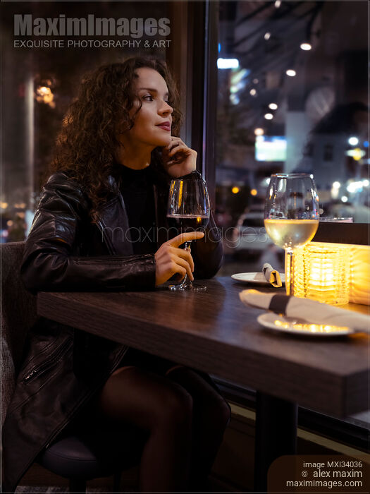 Portrait of an attractive woman in black leather coat sitting alone at a restaurant table with a glass of wine Stock photo of Portrait of an attractive woman in black leather coat sitting alone at a restaurant table with a glass of wine Buy commercial use license at MaximImages