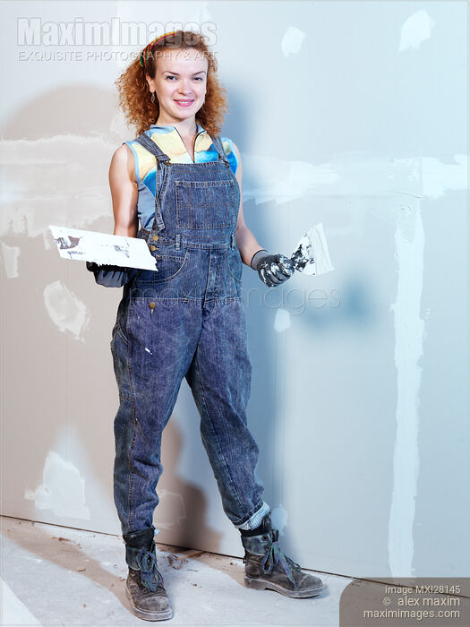 Stock photo of Portrait of woman construction worker patching up drywall Buy commercial use license at MaximImages