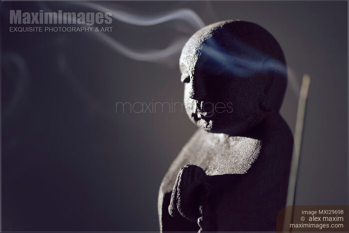 Praying Buddha statue with burning incense smoke Stock photo of Praying Buddha statue with burning incense smoke Buy commercial use license at MaximImages