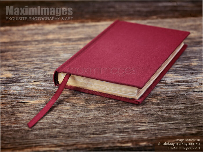 Stock photo of Red hardcover book on wooden background Buy commercial use license at MaximImages