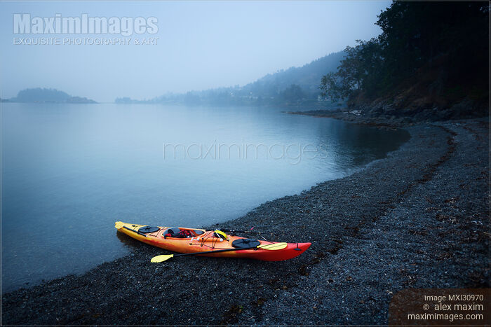 Stock photo of Red kayak on a sea shore in yearly morning mist Buy commercial use license at MaximImages