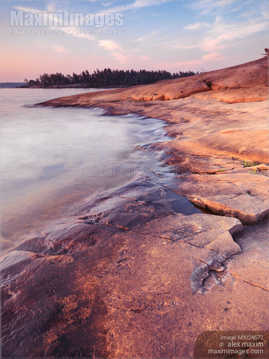 Red rocks on a lake shore at dawn Stock photo of Red rocks on a lake shore at dawn Buy commercial use license at MaximImages