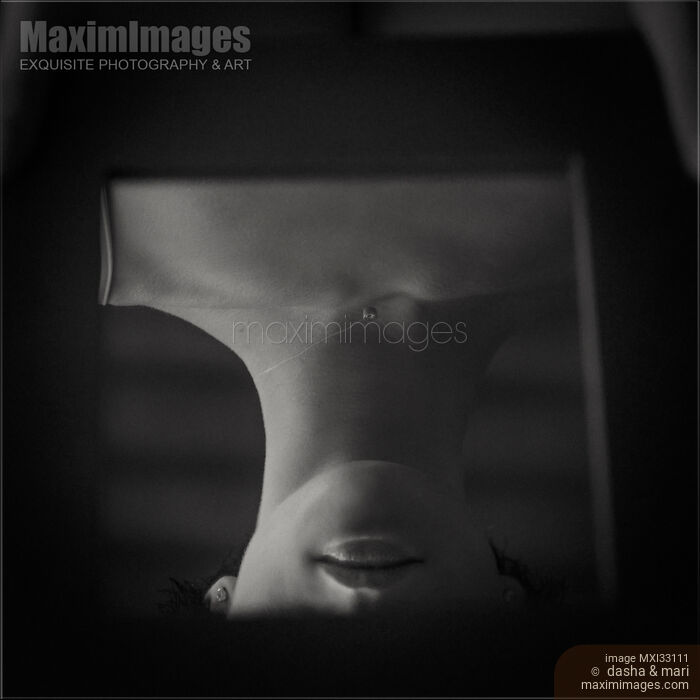 Stock photo of Reflection of a mysterious young woman delicate face partially obscured by the mirror frame Buy commercial use license at MaximImages