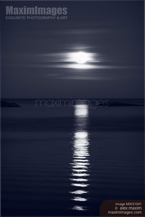 Stock photo of Rise of the Full Harvest Moon above Pacific ocean black and white Buy commercial use license at MaximImages