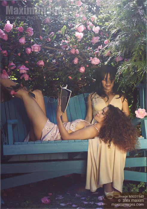Romantic lesbian couple resting on a bench in a garden woman reading a book lying on lap of another Stock photo of Romantic lesbian couple resting on a bench in a garden woman reading a book lying on lap of another Buy commercial use license at MaximImages
