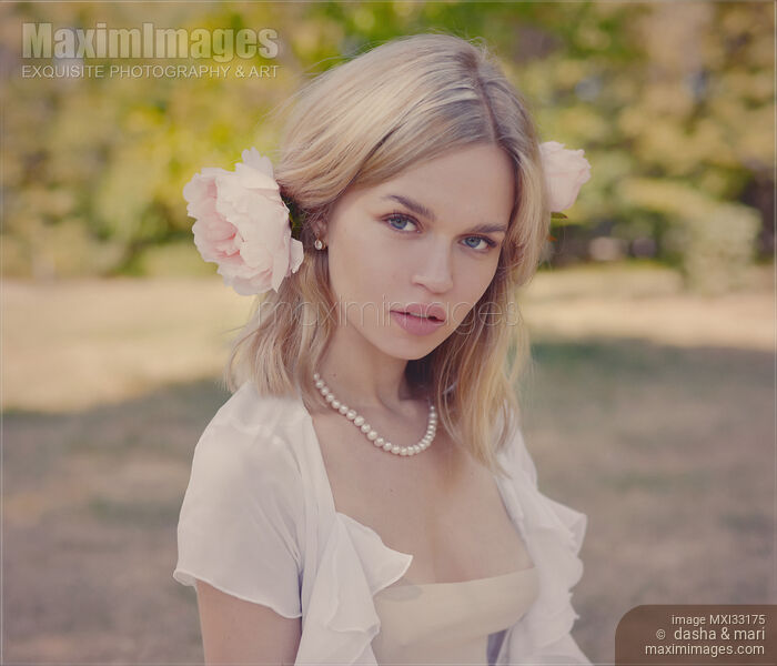 Romantic portrait of a young pretty woman with a pink flower in her blond hair Stock photo of Romantic portrait of a young pretty woman with a pink flower in her blond hair Buy commercial use license at MaximImages