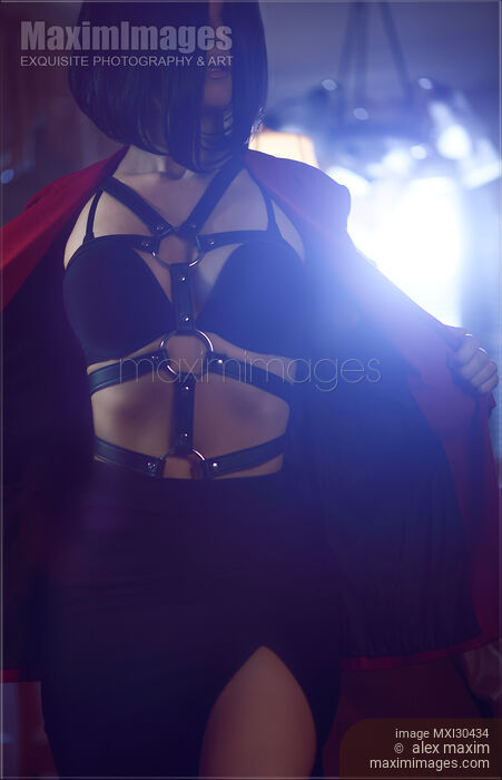 Stock photo of Seductive woman with undressing revealing sexy bondage leather harness and underwear in dim light Buy commercial use license at MaximImages