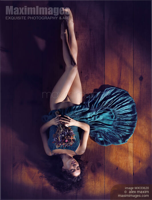 Sensual art nude portrait of woman in green dress with bare legs lying half naked on the floor with flowers Stock photo of Sensual art nude portrait of woman in green dress with bare legs lying half naked on the floor with flowers Buy commercial use license at MaximImages