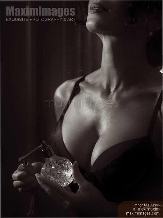 Sensual black and white beauty portrait of a woman in lingerie spraying perfume on her chest from a bottle Stock photo of Sensual black and white beauty portrait of a woman in lingerie spraying perfume on her chest from a bottle Buy commercial use license at MaximImages
