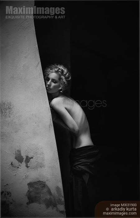 Stock photo of Sensual black and white portrait of a topless woman leaning against a rustic wall Buy commercial use license at MaximImages