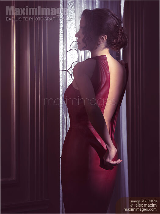Sensual boudoir portrait a woman in red leather dress pulling down zipper closure revealing her bare back in dim indoor night light Stock photo of Sensual boudoir portrait a woman in red leather dress pulling down zipper closure revealing her bare back in dim indoor night light Buy commercial use license at MaximImages