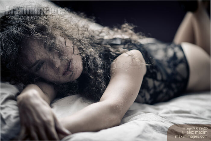 Stock photo of Sensual candid portrait of a young beautiful woman lying on a bed in underwear Buy commercial use license at MaximImages
