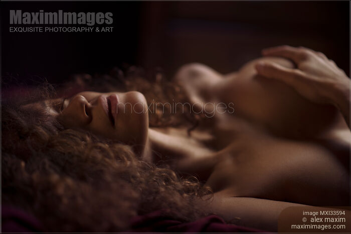 Stock photo of Sensual closeup portrait of a woman lying naked in bed with her hand on her breast Buy commercial use license at MaximImages