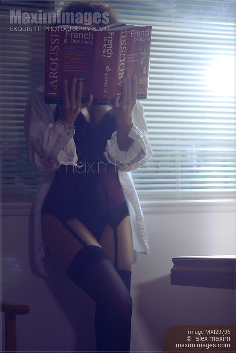 Sensual concept of sexy woman in corset and stockings reading French dictionary at night Stock photo of Sensual concept of sexy woman in corset and stockings reading French dictionary at night Buy commercial use license at MaximImages