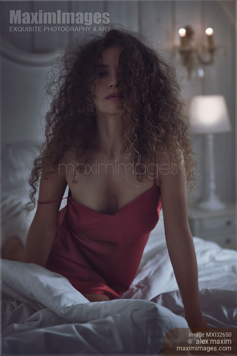 Sensual expressive portrait of a sexy woman with long curly hair in bed in dark bedroom Stock photo of Sensual expressive portrait of a sexy woman with long curly hair in bed in dark bedroom Buy commercial use license at MaximImages