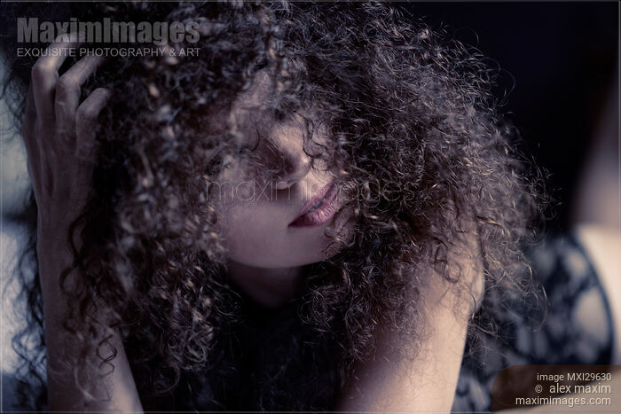 Sensual expressive portrait of a woman lying on a bed her face covered with long curly hair Stock photo of Sensual expressive portrait of a woman lying on a bed her face covered with long curly hair Buy commercial use license at MaximImages