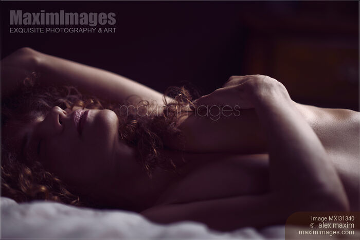 Sensual nude portrait of a woman lying naked in bed with her hand on her breasts Stock photo of Sensual nude portrait of a woman lying naked in bed with her hand on her breasts Buy commercial use license at MaximImages