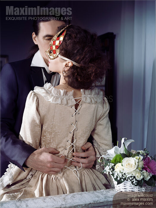 Sensual portrait of a couple, man unlacing corset dress back of a woman in Venetian carnival mask. Casanova romantic seduction concept. Stock photo of Sensual portrait of a couple, man unlacing corset dress back of a woman in Venetian carnival mask. Casanova romantic seduction concept. Buy commercial use license at MaximImages