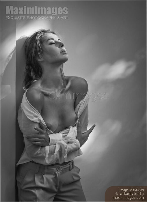 Sensual portrait of a woman standing topless leaning against a wall in open shirt with her breasts bared Stock photo of Sensual portrait of a woman standing topless leaning against a wall in open shirt with her breasts bared Buy commercial use license at MaximImages