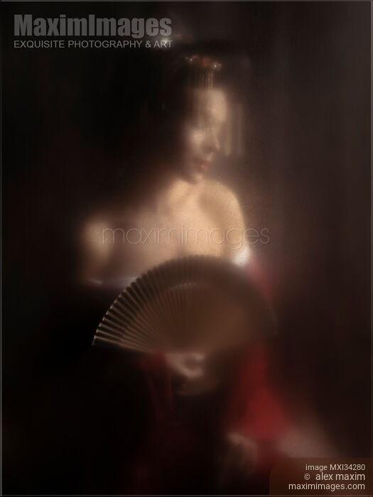Stock photo of Sensual portrait of beautiful Japanese geisha or courtesan with bared shoulders and a hand fan behind glass Buy commercial use license at MaximImages