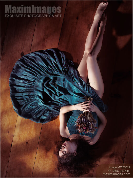 Sensual portrait of woman in green dress with bare legs lying on the floor holding flowers Stock photo of Sensual portrait of woman in green dress with bare legs lying on the floor holding flowers Buy commercial use license at MaximImages