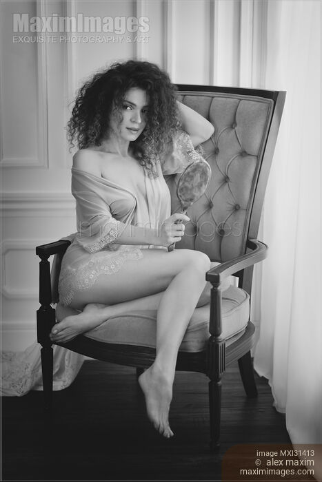 Sensual romantic black and white portrait of a girl sitting in a chair with a hand mirror barely dressed in pink lacy underwear Stock photo of Sensual romantic black and white portrait of a girl sitting in a chair with a hand mirror barely dressed in pink lacy underwear Buy commercial use license at MaximImages