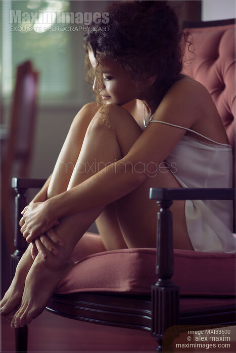 Sensual romantic portrait of young woman in night shirt sitting in armchair cuddled up Stock photo of Sensual romantic portrait of young woman in night shirt sitting in armchair cuddled up Buy commercial use license at MaximImages