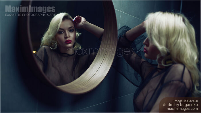 Stock photo of Sexy blond woman looking into a round mirror Buy commercial use license at MaximImages