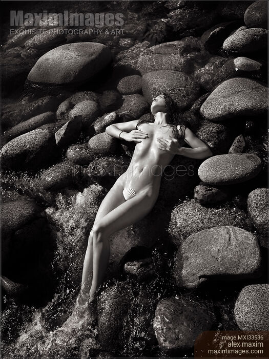 Sexy nude woman lying on rocks in water with her sensual wet naked body barely covered with sea shell Black and white Stock photo of Sexy nude woman lying on rocks in water with her sensual wet naked body barely covered with sea shell Black and white Buy commercial use license at MaximImages