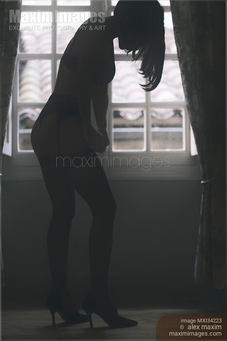 Sexy silhouette of a woman in lingerie putting on black stockings in a dark room by the window Stock photo of Sexy silhouette of a woman in lingerie putting on black stockings in a dark room by the window Buy commercial use license at MaximImages