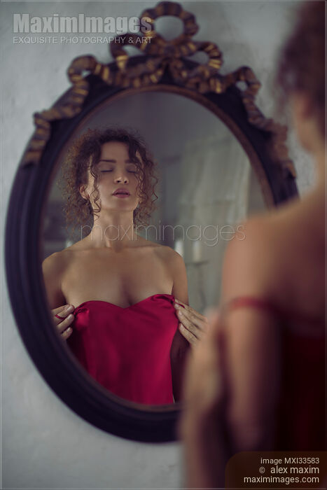 Sexy woman in red silky nightgown by the mirror with male hands undressing her from behind Stock photo of Sexy woman in red silky nightgown by the mirror with male hands undressing her from behind Buy commercial use license at MaximImages