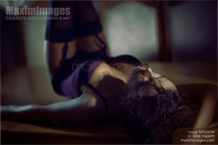 Sexy woman lying on dining table in corset and stockings in dark room Stock photo of Sexy woman lying on dining table in corset and stockings in dark room Buy commercial use license at MaximImages