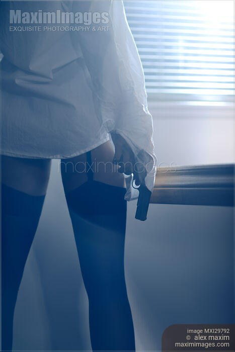 Sexy woman standing by the window with a gun in her hand wearing shirt and stockings Stock photo of Sexy woman standing by the window with a gun in her hand wearing shirt and stockings Buy commercial use license at MaximImages