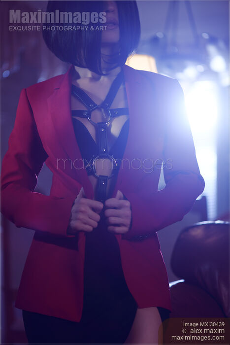 Stock photo of Sexy woman with short black hair wearing bondage leather harness and underwear under a red suit jacket Buy commercial use license at MaximImages
