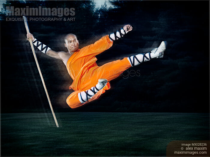 Stock photo of Shaolin warrior monk performing flying kick with a staff Buy commercial use license at MaximImages
