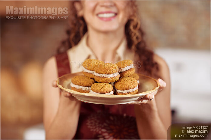 Stock photo of Smiling woman with a plate of freshly baked home-made cookies Buy commercial use license at MaximImages