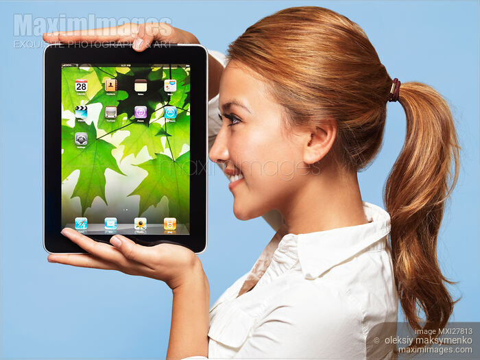 Stock photo of Smiling young woman looking at Apple iPad tablet Buy commercial use license at MaximImages