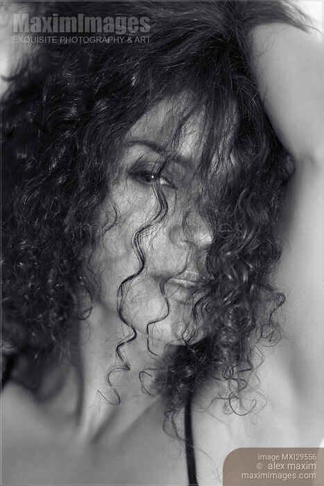 Sultry beauty face portrait of young woman looking through her long curly dark hair Black and white Stock photo of Sultry beauty face portrait of young woman looking through her long curly dark hair Black and white Buy commercial use license at MaximImages